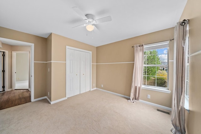 unfurnished bedroom featuring a ceiling fan, a closet, carpet floors, baseboards, and visible vents