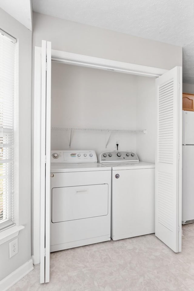 laundry area with washing machine and clothes dryer, laundry area, and a textured ceiling