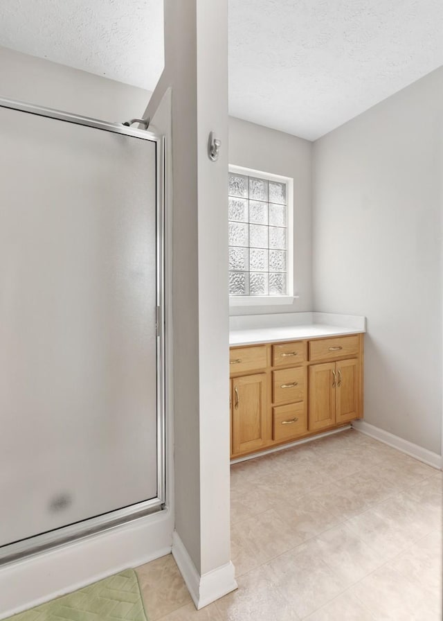 bathroom featuring baseboards, a stall shower, and a textured ceiling