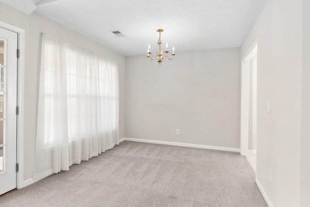 carpeted empty room with visible vents, baseboards, and an inviting chandelier