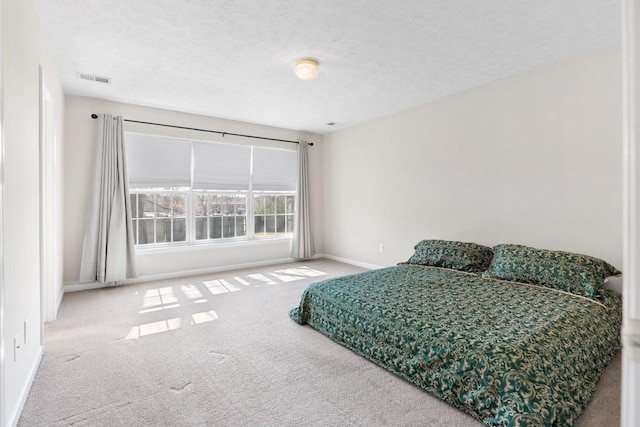 bedroom featuring carpet flooring, visible vents, a textured ceiling, and baseboards