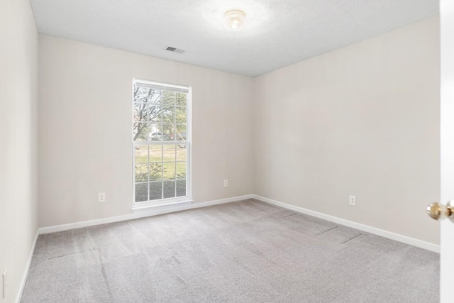 carpeted spare room with visible vents and baseboards