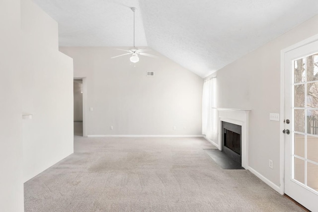 unfurnished living room with ceiling fan, a fireplace with flush hearth, visible vents, vaulted ceiling, and carpet floors