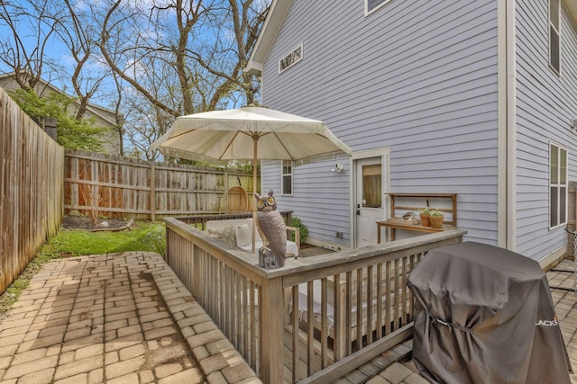 wooden terrace featuring a fenced backyard, outdoor dining area, area for grilling, and a patio