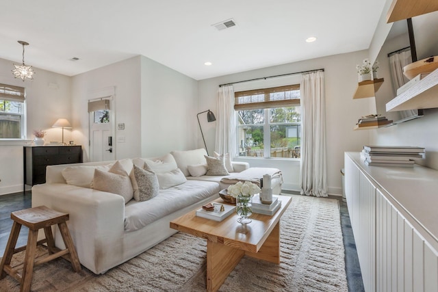living area featuring healthy amount of natural light, baseboards, wood finished floors, recessed lighting, and a chandelier