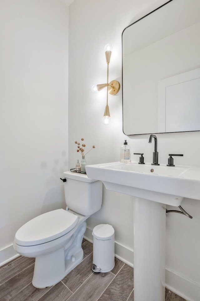 half bath featuring toilet, baseboards, and wood finished floors