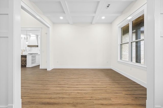 empty room with visible vents, baseboards, beamed ceiling, and wood finished floors