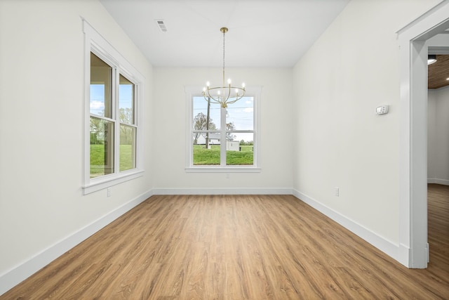 unfurnished dining area with a notable chandelier, light wood-type flooring, and baseboards