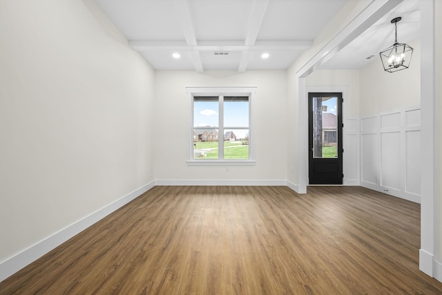 unfurnished room featuring beamed ceiling, baseboards, a notable chandelier, and wood finished floors