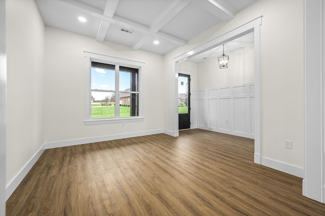 empty room featuring baseboards, dark wood-type flooring, visible vents, beamed ceiling, and coffered ceiling