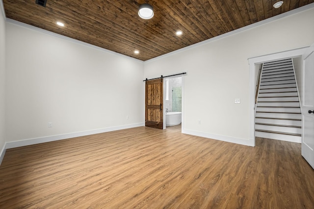 unfurnished room featuring baseboards, stairway, a barn door, wood ceiling, and wood finished floors