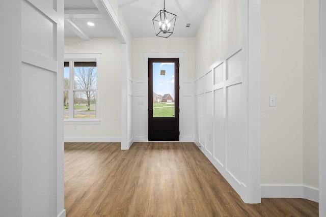 entryway with a decorative wall, baseboards, an inviting chandelier, and wood finished floors