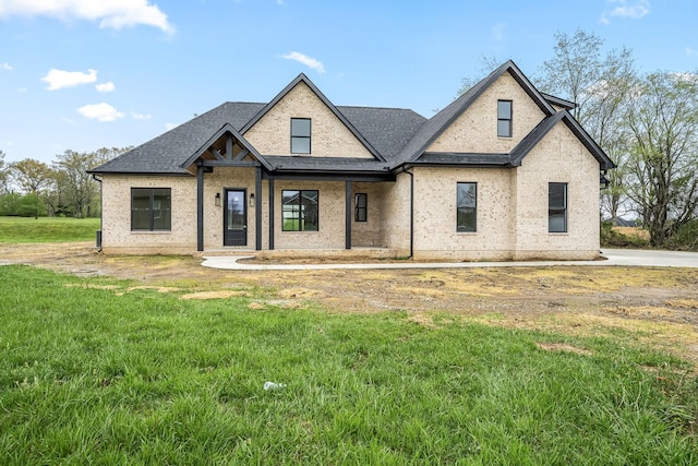modern farmhouse style home featuring roof with shingles, a front lawn, and brick siding