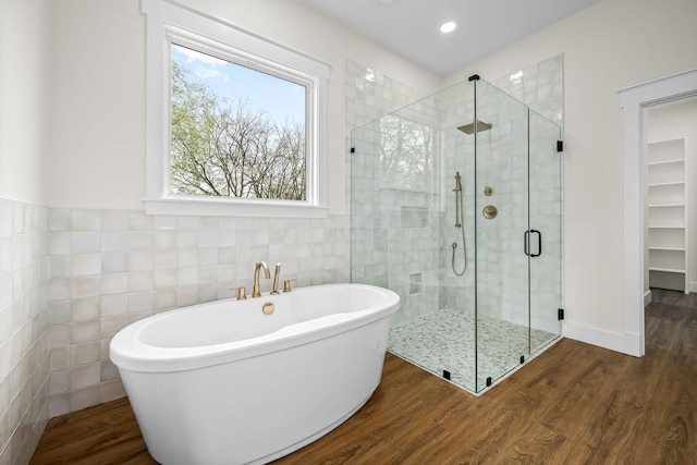 full bathroom with recessed lighting, wood finished floors, a freestanding bath, tile walls, and a stall shower