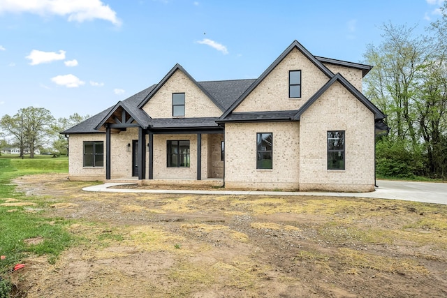 view of front of home featuring roof with shingles and brick siding