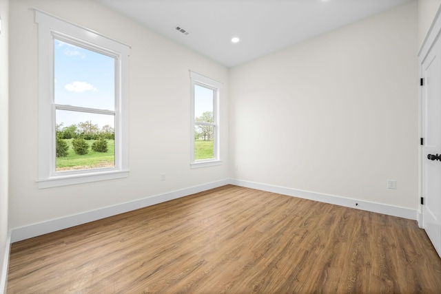 unfurnished room with wood finished floors, baseboards, visible vents, and recessed lighting