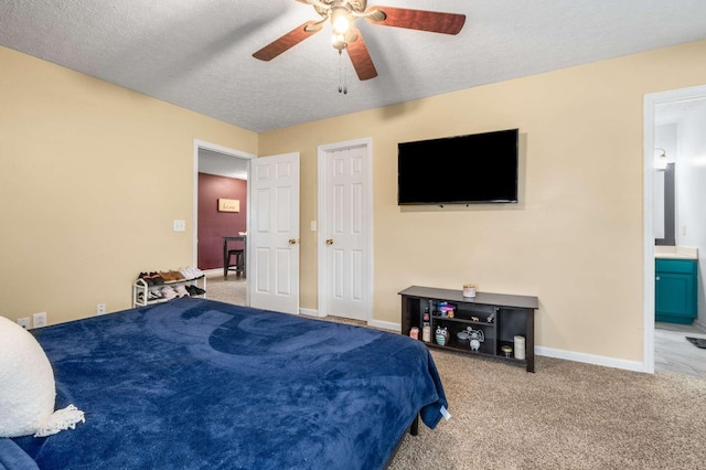 carpeted bedroom featuring a textured ceiling, ceiling fan, baseboards, and ensuite bath