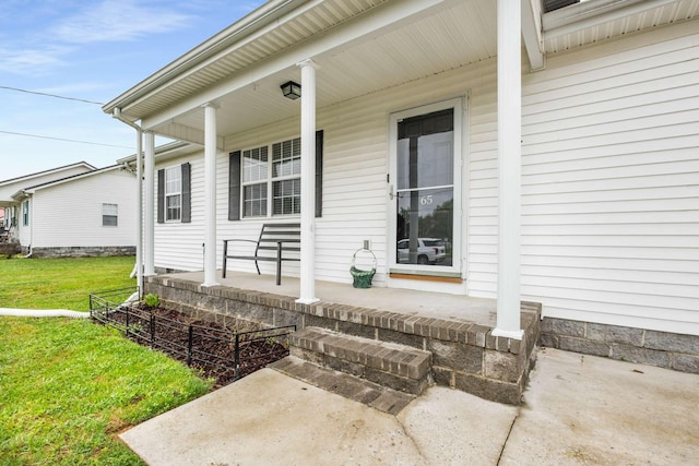 view of exterior entry with a lawn and covered porch