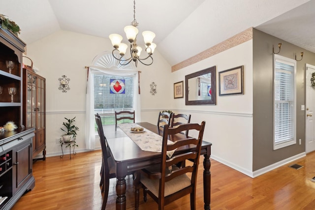 dining room with visible vents, baseboards, an inviting chandelier, light wood finished floors, and vaulted ceiling