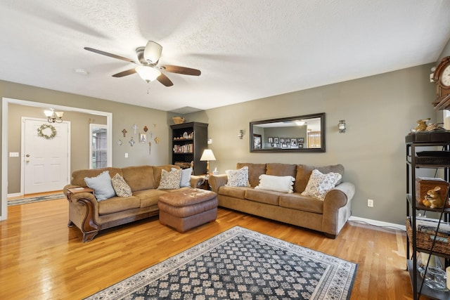 living room with light wood-style floors, ceiling fan, baseboards, and a textured ceiling