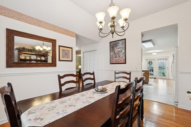dining area featuring wood finished floors, a notable chandelier, and lofted ceiling