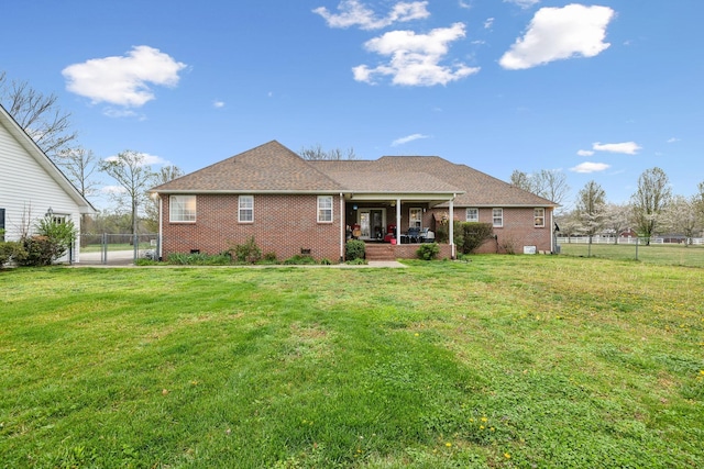 rear view of house with fence, a yard, brick siding, and a gate