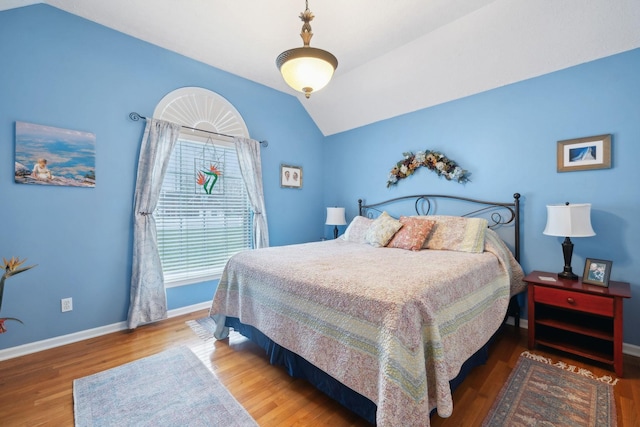 bedroom with wood finished floors, baseboards, and vaulted ceiling