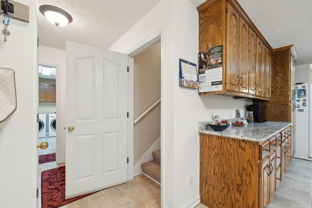 bar featuring freestanding refrigerator, a textured ceiling, stairs, baseboards, and washing machine and dryer