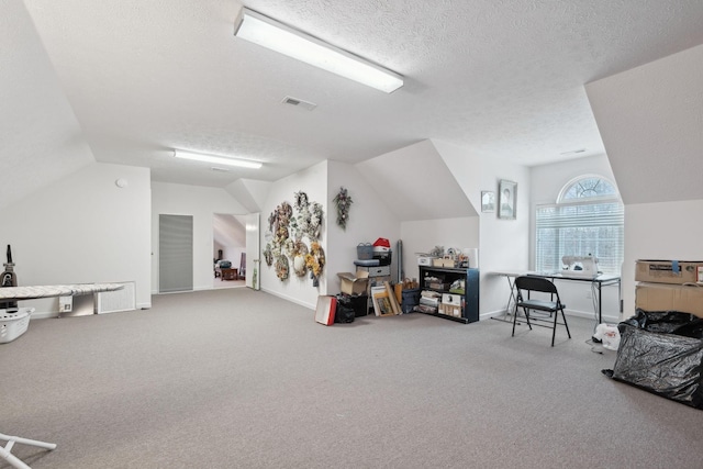 playroom featuring carpet, a textured ceiling, vaulted ceiling, visible vents, and baseboards