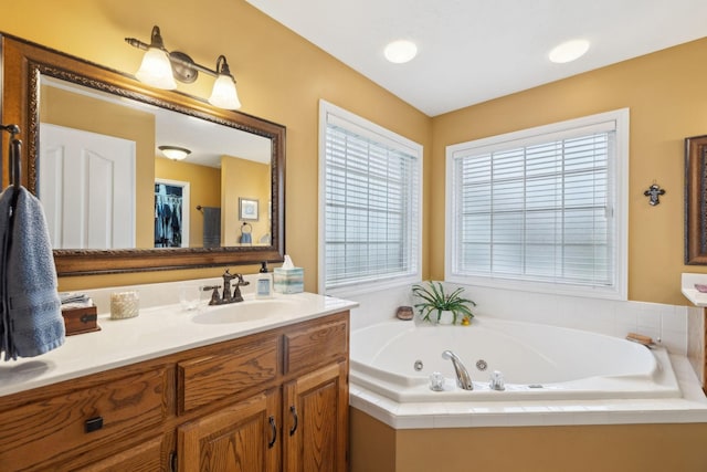 full bath featuring plenty of natural light, a tub with jets, and vanity