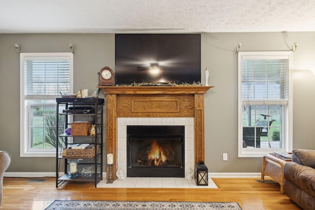 living room with a wealth of natural light, a textured ceiling, wood finished floors, and a fireplace