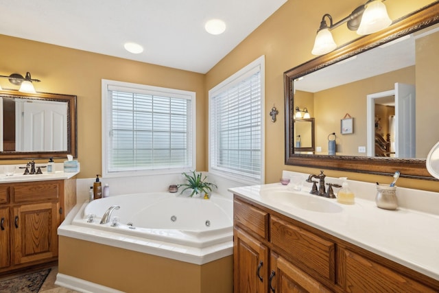full bath with a jetted tub, two vanities, and a sink