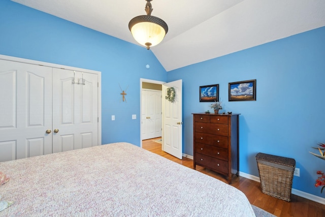 bedroom featuring a closet, baseboards, wood finished floors, and vaulted ceiling