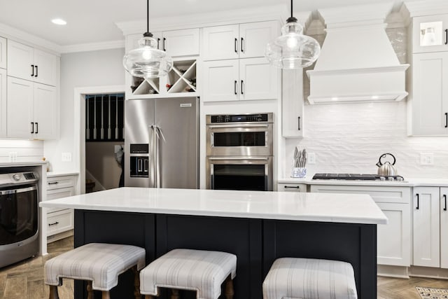 2009 Cedarmont Dr, Franklin, TN 37067 - kitchen with crown molding, custom exhaust hood, appliances with stainless steel finishes, washer / dryer, and a breakfast bar area