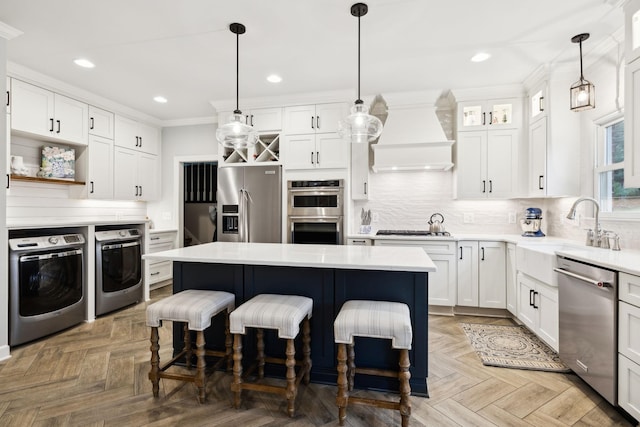 2009 Cedarmont Dr, Franklin, TN 37067 - kitchen with washer and dryer, ornamental molding, appliances with stainless steel finishes, a kitchen bar, and custom range hood