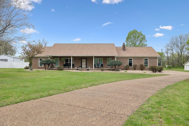 single story home with a chimney, a front lawn, brick siding, fence, and covered porch