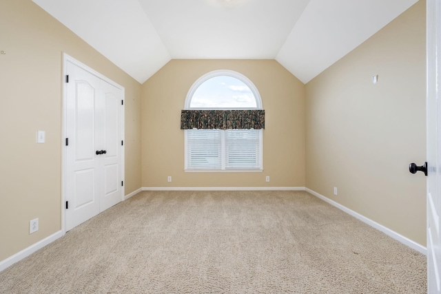 carpeted empty room featuring baseboards and lofted ceiling