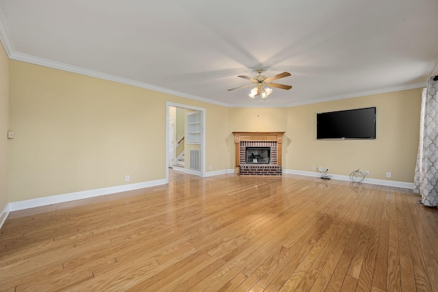 unfurnished living room with light wood-style flooring, ornamental molding, a ceiling fan, stairway, and a brick fireplace