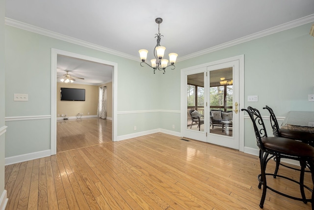 dining area with baseboards, light wood-type flooring, crown molding, visible vents, and ceiling fan with notable chandelier