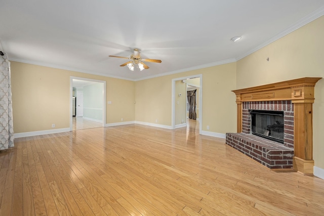 unfurnished living room featuring light wood-style flooring, ornamental molding, ceiling fan, and a fireplace