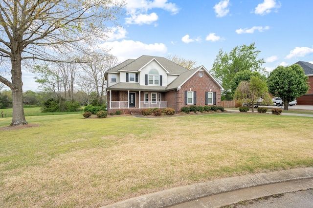 traditional-style house featuring covered porch, a front lawn, and brick siding