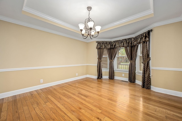 empty room featuring a notable chandelier, crown molding, and a raised ceiling