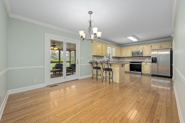 kitchen with a peninsula, appliances with stainless steel finishes, ornamental molding, and a kitchen breakfast bar