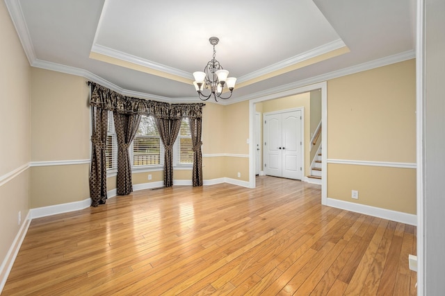 spare room featuring a chandelier, baseboards, and a raised ceiling