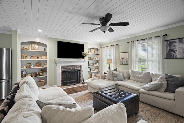 living area featuring built in shelves, ceiling fan, wood ceiling, a fireplace, and ornamental molding