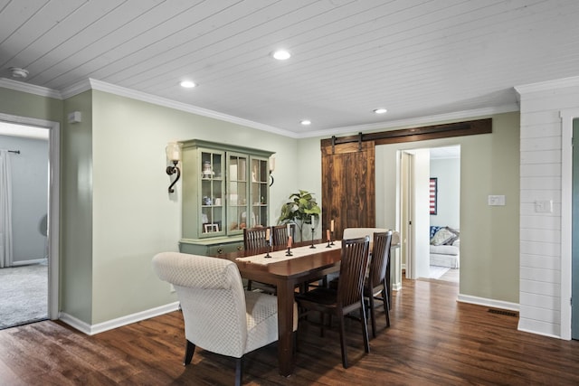 dining space with baseboards, dark wood-style flooring, ornamental molding, and a barn door