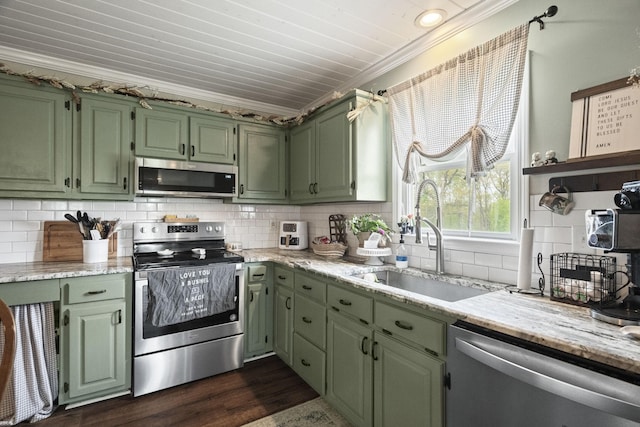kitchen with stainless steel appliances, ornamental molding, a sink, green cabinets, and decorative backsplash