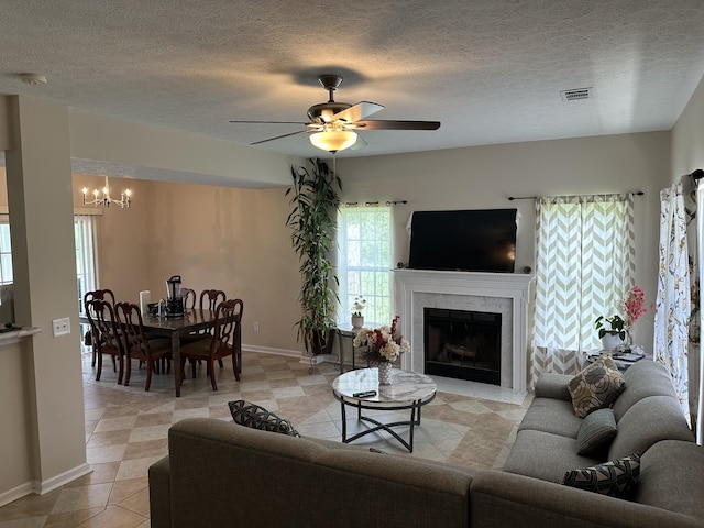 8257 Ramstone Way, Antioch, TN 37013 - living room featuring ceiling fan with notable chandelier, a textured ceiling, visible vents, a premium fireplace, and baseboards