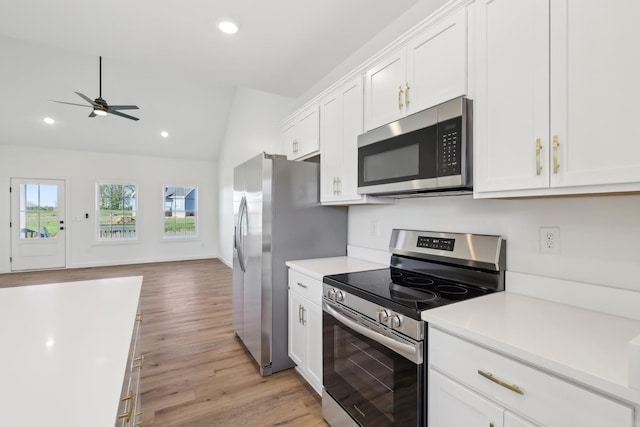 kitchen with light countertops, white cabinets, appliances with stainless steel finishes, and vaulted ceiling