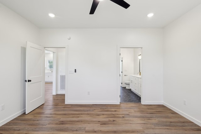 unfurnished bedroom featuring ensuite bathroom, recessed lighting, wood finished floors, and visible vents